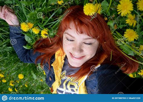 Girl With Freckles Red Haired Happy Young Woman Lying On The Grass On A Dandelion Field Stock