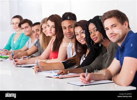 Portrait Of Multiethnic College Students Sitting In A Row At Desk Stock