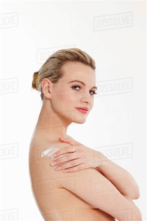 Studio Portrait Of Beautiful Naked Blond Babe Woman Applying Moisturiser To Shoulder Stock
