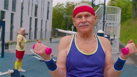 Senior Man Grandfather Doing Training Weightlifting Exercising With Dumbbells On Playground In