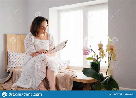 Mid Age Adult Woman Plus Size Reading A Book By The Window Stock Image Image Of Read Body