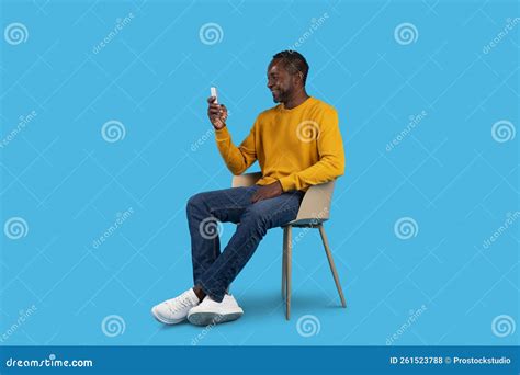 Relaxed Black Man Chilling On Blue Using Cell Phone Stock Photo