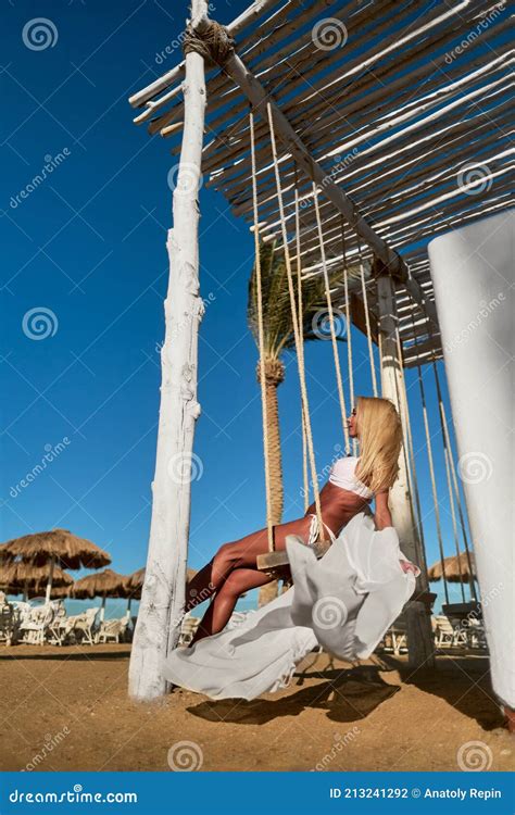 Beautiful Young Woman In Pareo Swinging On A Swing During Sunny Day At