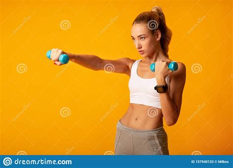 Young Woman Doing Dumbbell Boxing Workout On Yellow Background Stock