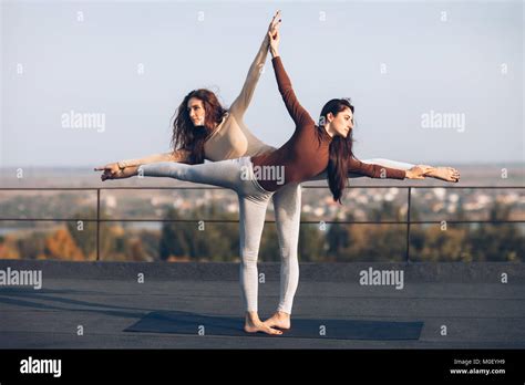 Two Young Beautiful Women Doing Yoga Asana Virabhadrasana Helping Each