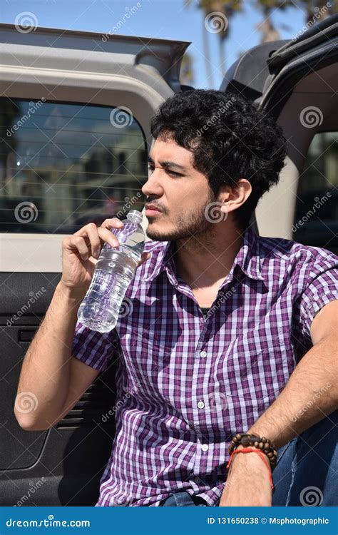 A Handsome Young Man Drinking Bottled Water Outdoors Stock Photo
