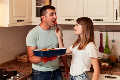 Padre E Hija Mirando A La Cámara En La Cocina Foto Gratis