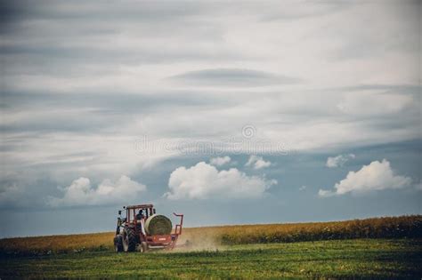 View Of A Tractor On A Dried Field Under The Blue Cloudy Sky Stock