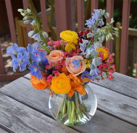 A Glass Vase Filled With Colorful Flowers On Top Of A Wooden Table