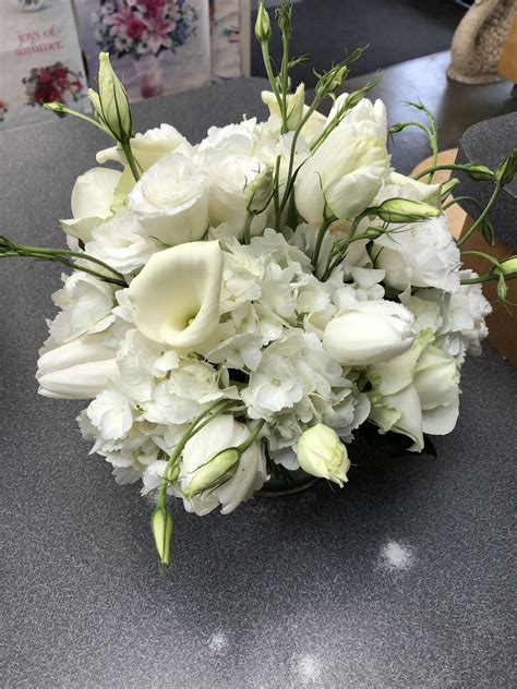 A Bouquet Of White Flowers Sitting On Top Of A Table Next To A Pair Of