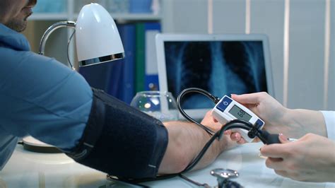 Nurse Taking Blood Pressure For Man Close Up Of Doctor Care Patient