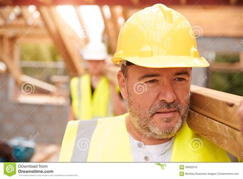 First year carpenter or builders apprentice. Builder And Apprentice Carrying Wood On Construction Site ...