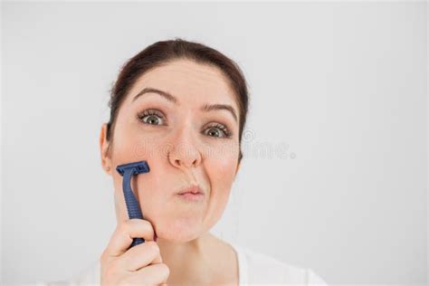 caucasian funny woman shaves her face with a straight razor on a white background copy space