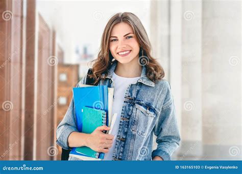 Beautiful Girl Student Smiling Against University And Holds Notebooks