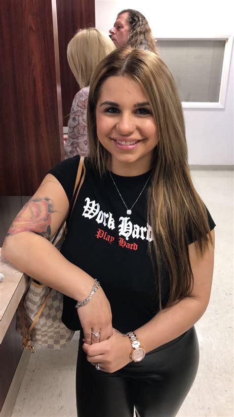 A Woman With Long Hair And Tattoos Standing In Front Of A Counter