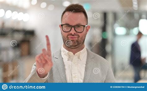 Portrait Of Serious Caucasian Young Man Saying No By Finger Sign Stock