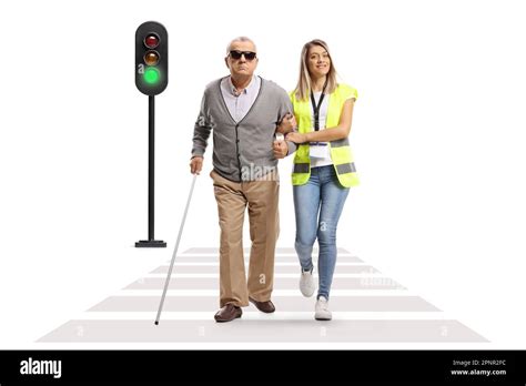 Female Community Worker Helping An Elderly Blind Man Crossing Street