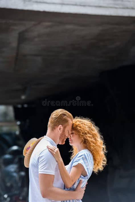 Side View Of Redhead Couple Embracing Each Other And Standing Face To