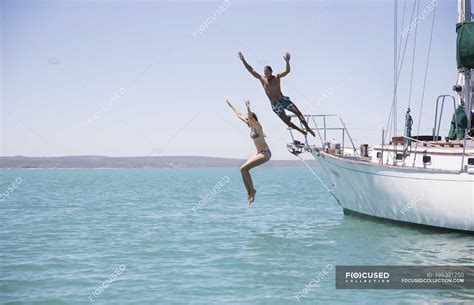 Couple Jumping Off Boat Into Water Blue Sky Full Length Stock