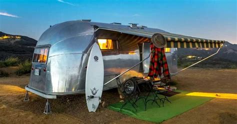 An Airstream Sits In The Middle Of A Field At Night With Its Lights On