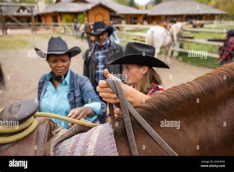 Rancher Helping Senior Woman Mount Horse For Horseback Riding Stock