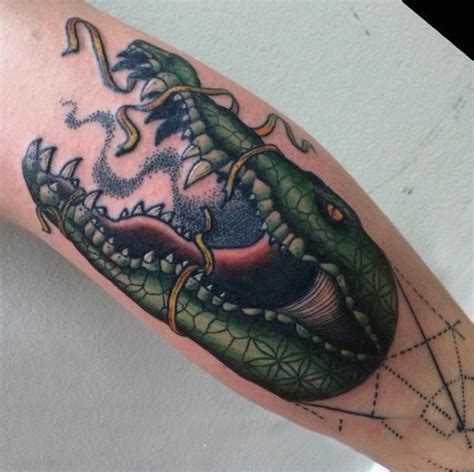 Alligators are still feared since they appeared millions of years ago. Old school colored alligator head with ribbon tattoo on ...