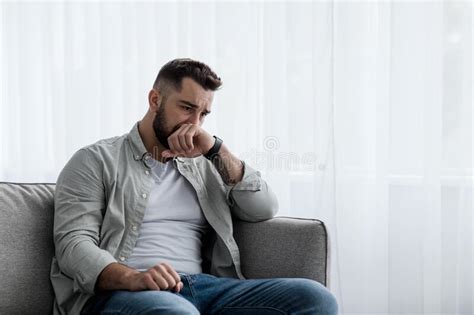 Depressed Sad Attractive Man Crying On Sofa At Home Feeling Lonely