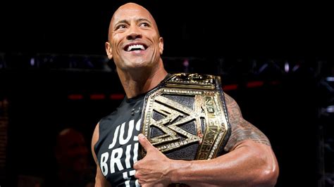 the rock smiling and holding his wwe championship belt