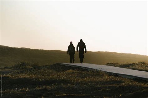 Silhouette Of Two People Walking Away In To The Distance At Sunset