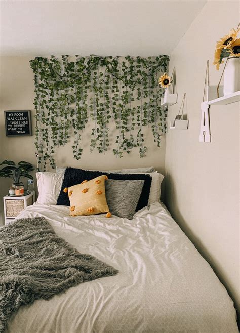 A White Bed Topped With Pillows Next To A Green Plant Wall Hanging On