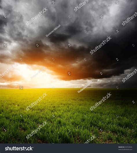 Storm Dark Clouds And Light Over Field With Green Grass Stock Photo