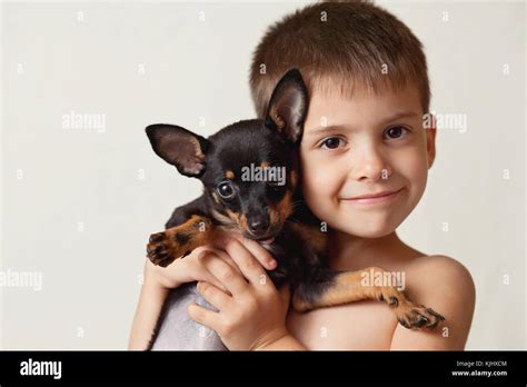 Portrait Of A Smiling Boy Cuddling His Miniature Pinscher Puppy Dog