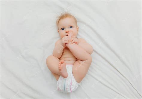 Premium Photo A Happy Baby In Diapers Is Lying On A White Bed And