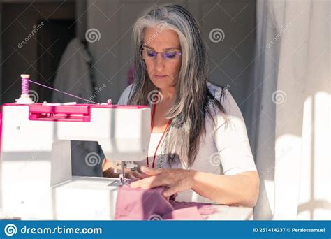 Gray Haired Seamstress Sewing A Piece Of Fabric On A Sewing Machine