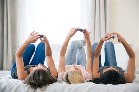 Op Het Bed Liggen En Meisjes Die Smartphones Gebruiken Stock Afbeelding