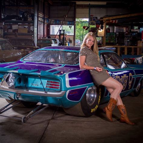 A Woman Posing Next To A Car In A Garage