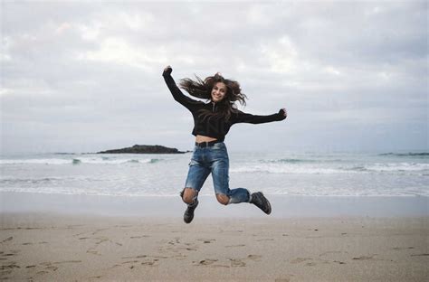 Happy Woman Jumping In The Air On The Beach Stock Photo