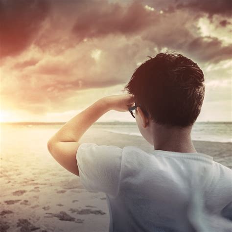 Boy Standing On The Beach At Sunset And Looking Forward
