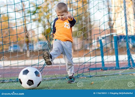 A Little Boy Plays Soccer In A City Park Gives A Pass Kicks A Ball