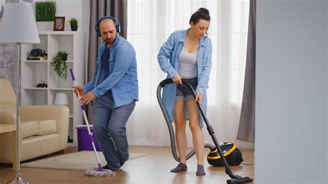 Premium Photo Cheerful Man Dancing While Cleaning The House Together With His Wife