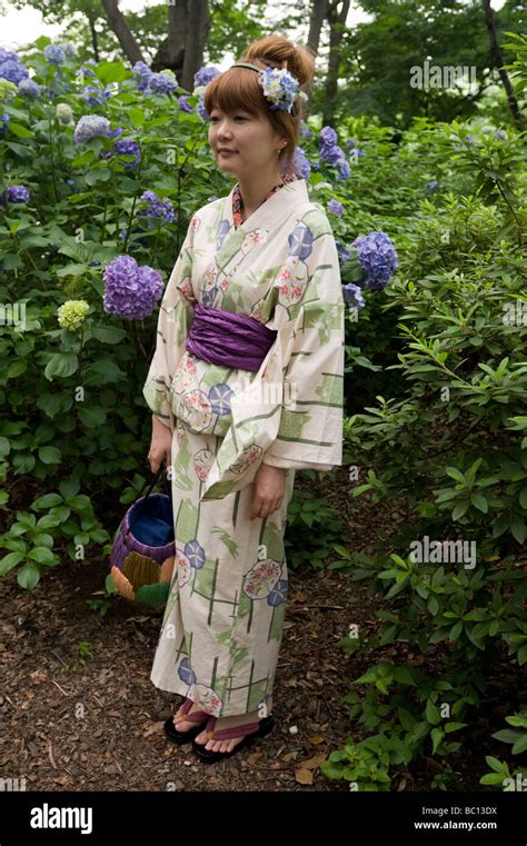 A Young Japanese Woman Poses In A Seasonal Kimono In Front Of The