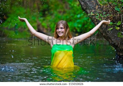 female woman nude model standing under the rain waist deep in water on a green background of