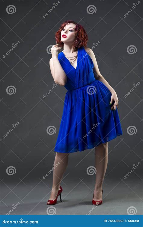 Young Beautiful Red Haired Caucasian Woman In Blue Dress Posing In