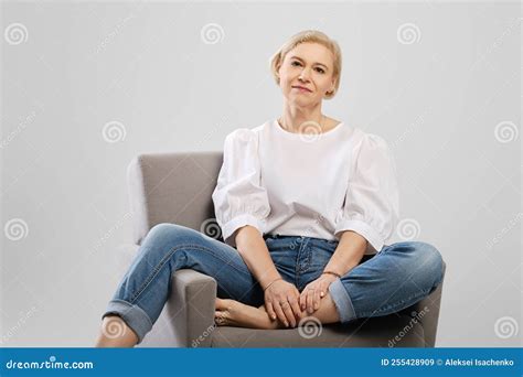 Positive Mature Woman Sitting In An Armchair In Studio Stock Image