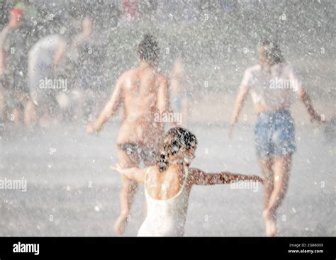 Women And Girl Walk Through Water Fountain Seen Through Sprays And