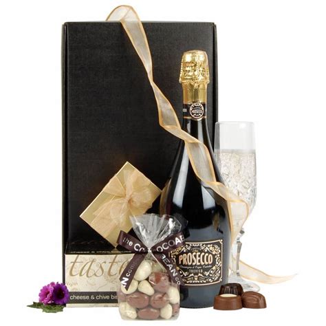 A bottle of prosecco displayed with flowers, with lindor chocolates and a yankee candle in a square hat box. Prosecco and Chocolate Treats Gift | Funky Hampers
