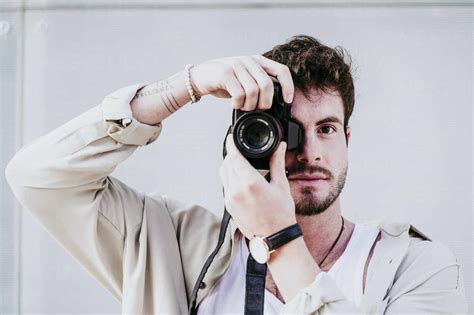 Confident Man Taking Photograph Through Camera While Standing Against