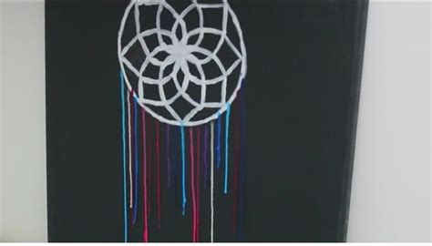 A White Dream Catcher Hanging From The Side Of A Black Wall With
