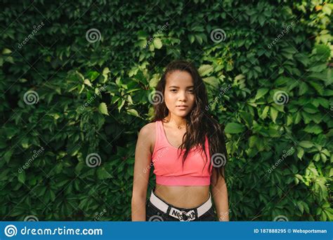 Stylish Mulatto Girl In A Pink T Shirt Stands On The Background Of A