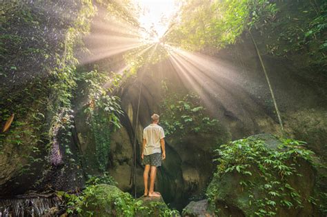 Travel Man Standing In Tropical Rainforest Cave Looking Up At The